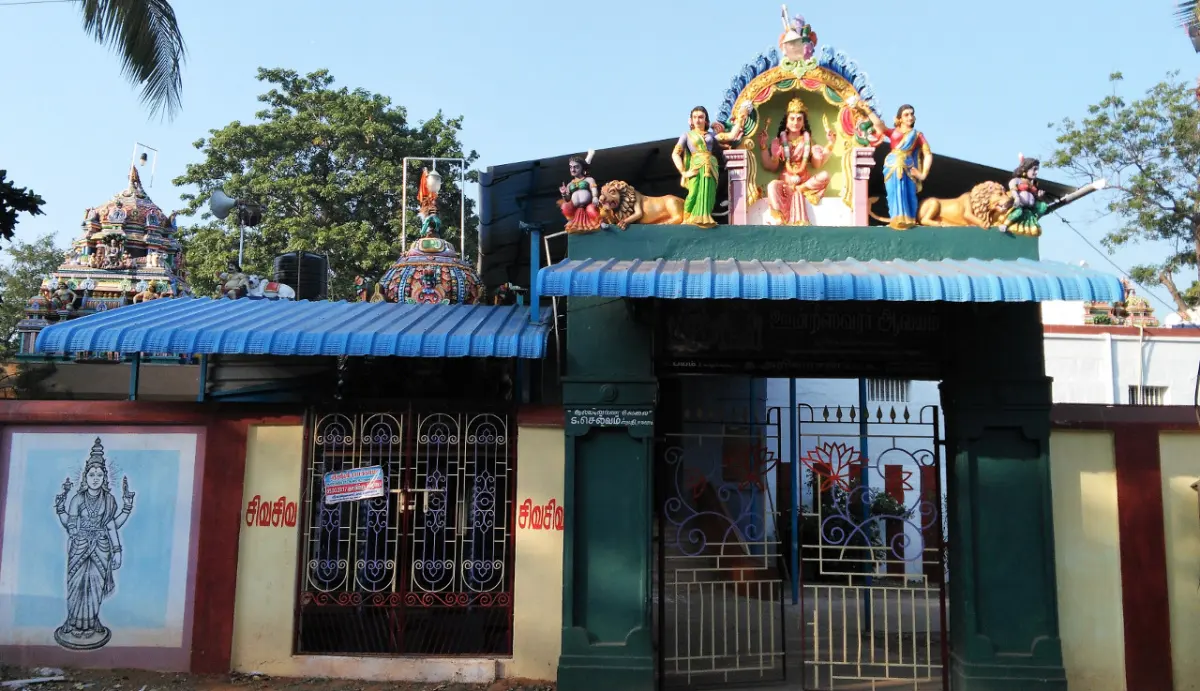 A gateway with colourful sculpted figures on top and a painted deity on the wall to its left.