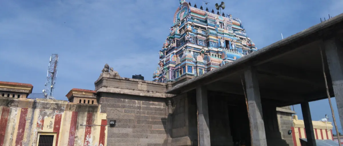 Colourful three-tier tower rising behind a granite wall and hall roof