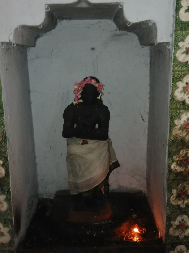 Black standing figure with garland and white cloth
