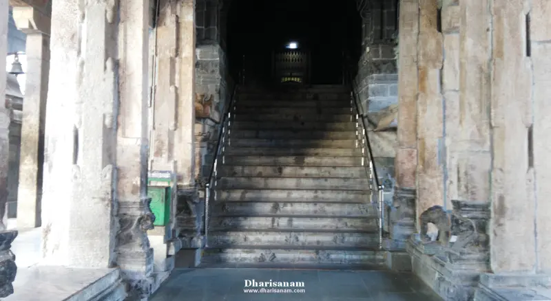 A wide stone staircase between carved pillars rising to a dim doorway.