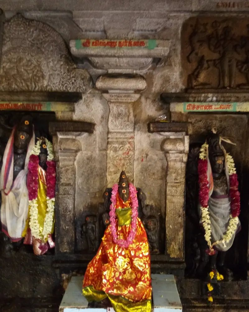 A small image in red and gold cloth in front, with garlanded images in niches at each side