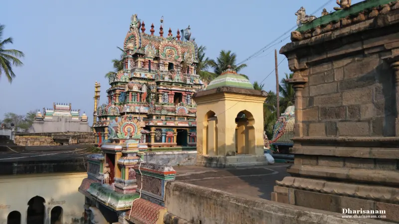 A colourful sculptured tower beside stone and plaster shrines