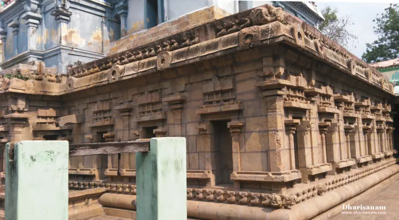 The old stone wall of a shrine with carved pilasters and mouldings, a wooden bar across the entrance at the left