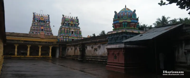 Paved courtyard with two towers beyond, a domed shrine at the right and a tin-roofed hall