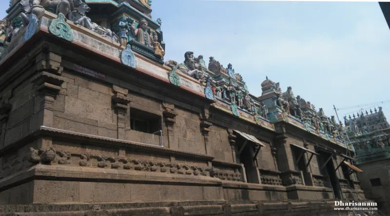 A tall wall of carved stone blocks with a tower of painted figures above it