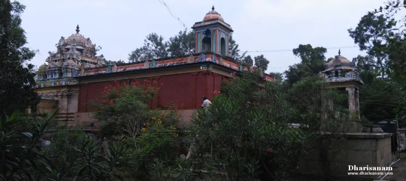 A long red wall with a painted roof edge and a bell tower, with a tower on the left and a small pavilion at right.