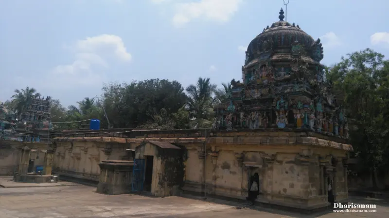 A domed tower with sculptures above a plain stone building, seen across an open courtyard.