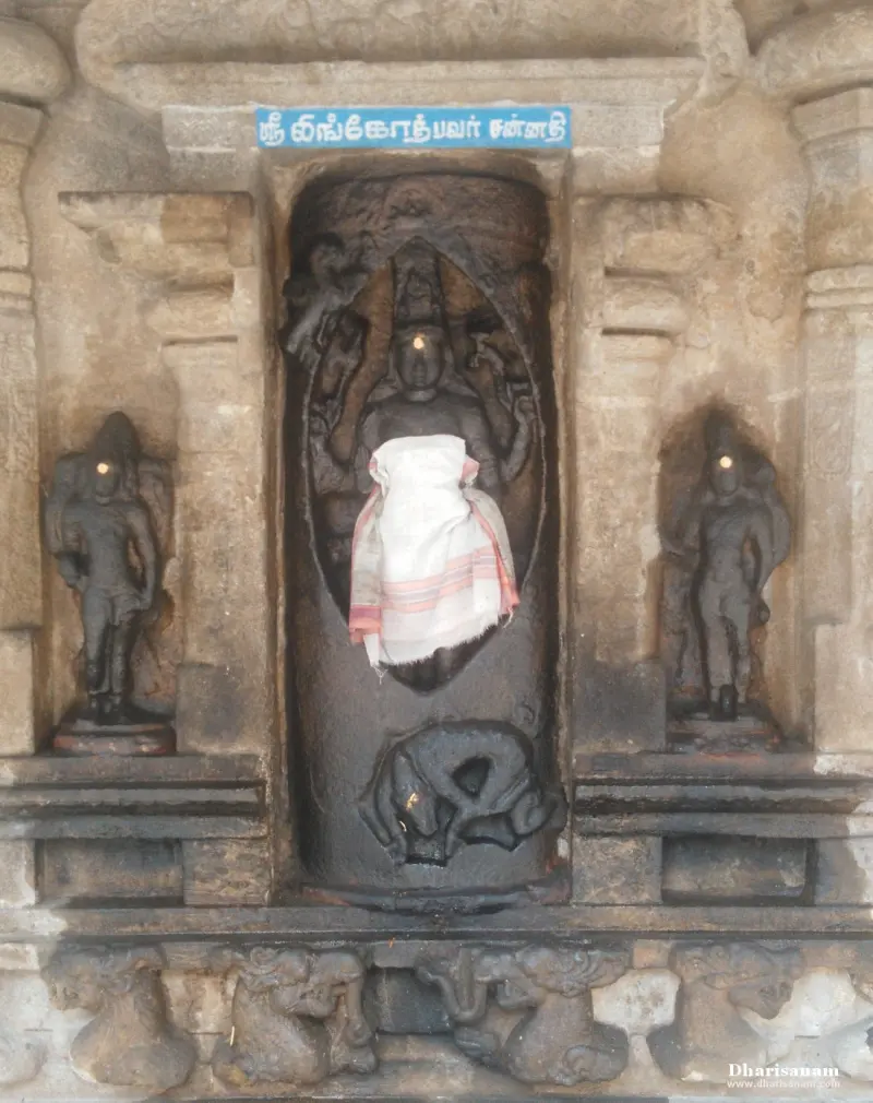 Black stone Lingothbavar figure inside a lingam-shaped niche, with an attendant on each side