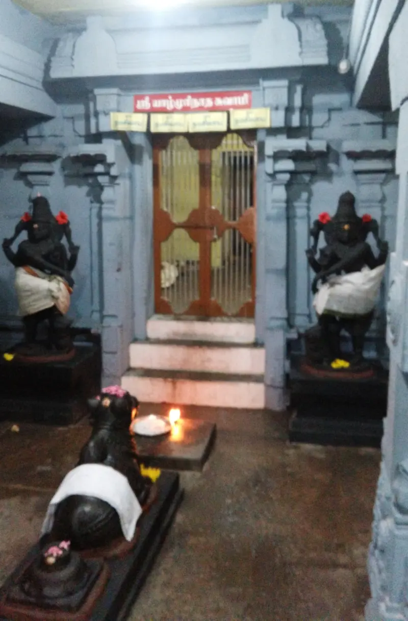 Wooden-framed door with a lamp before it, flanked by two dark guardian figures, with Nandi in front.