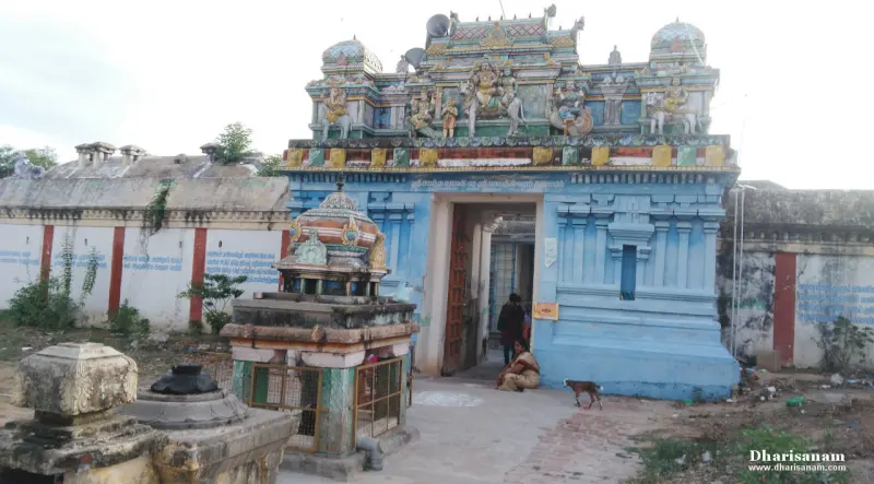 A blue entrance tower with sculptures above, and people sitting near the doorway.