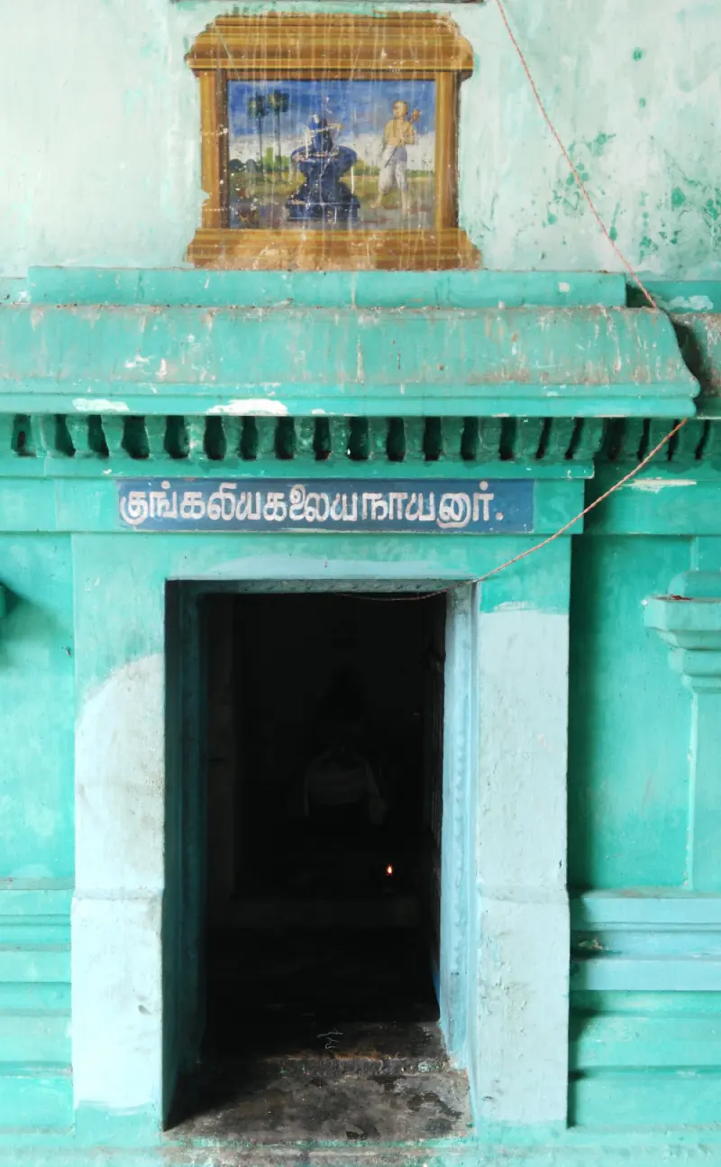 Turquoise doorway with a name board and painting above