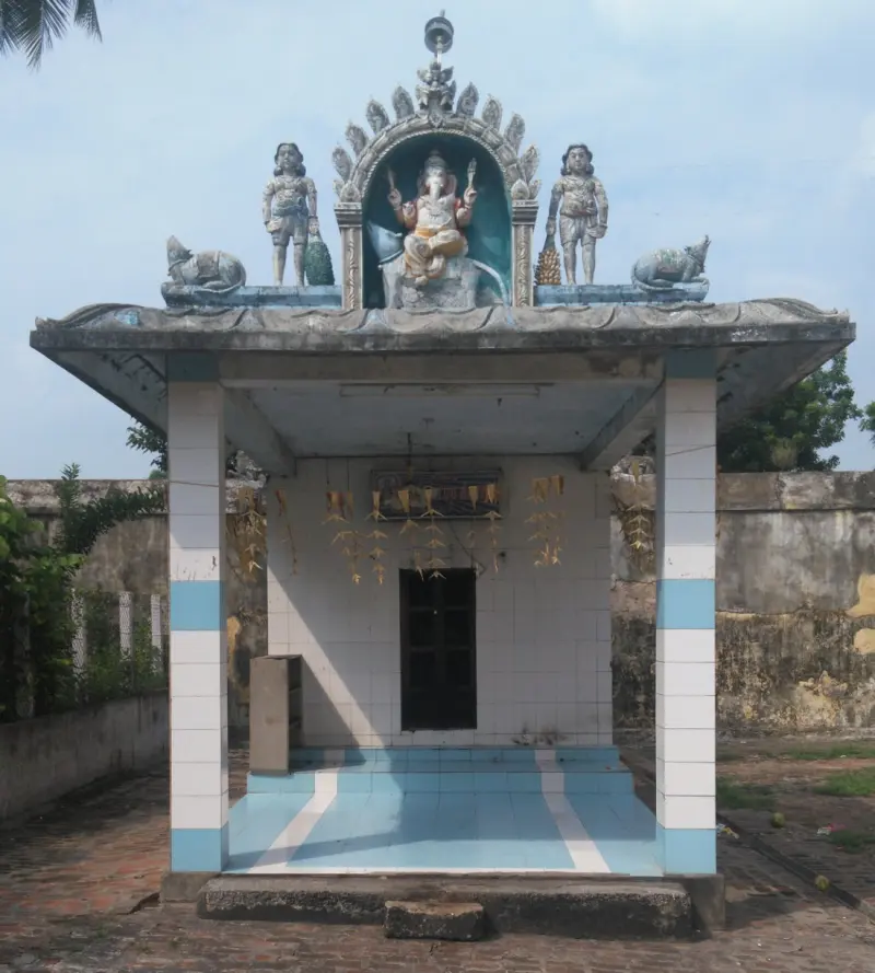 A small tiled shrine with a seated Vinayakar figure above its roof