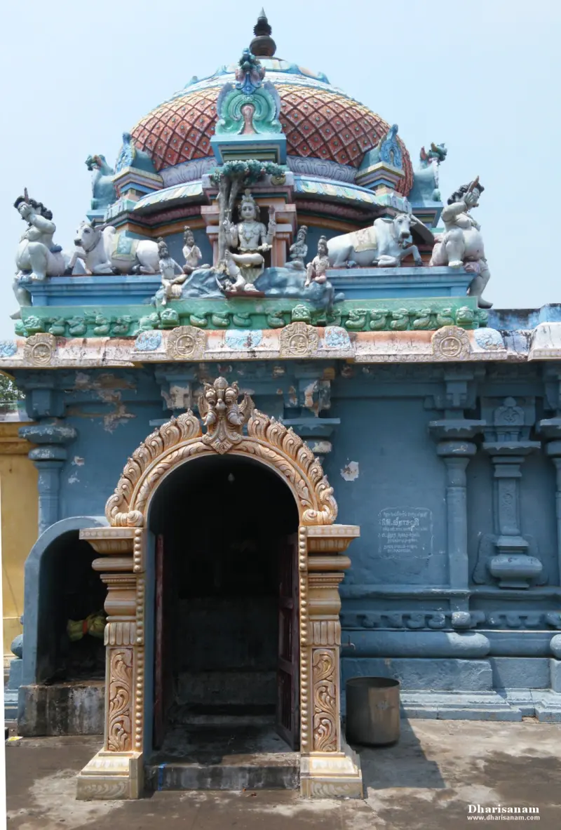 A blue stone shrine with a coloured dome, painted figures and an arched doorway