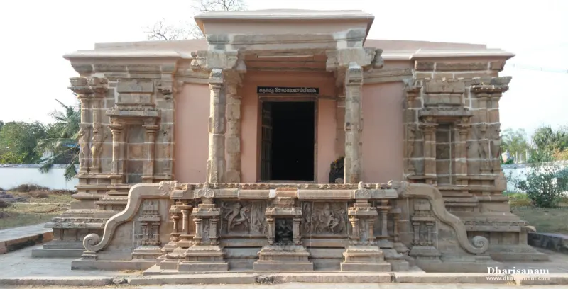 Small stone shrine with a pillared front and a dark doorway, standing on a carved base