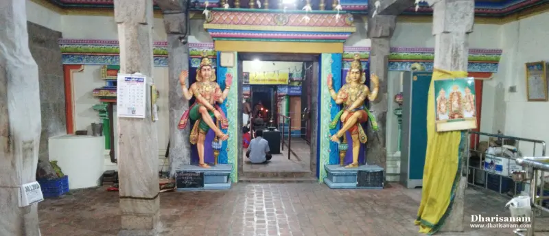 A pillared hall with two painted guardian figures at a lit inner doorway
