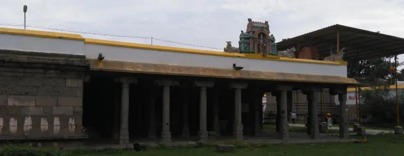 A long open hall with a row of stone pillars under a flat roof, a painted tower above its far end.