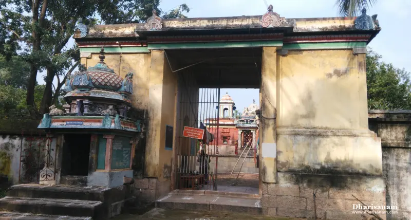 A yellow gateway with a small shrine on its left; the temple's red walls show through the open gate.