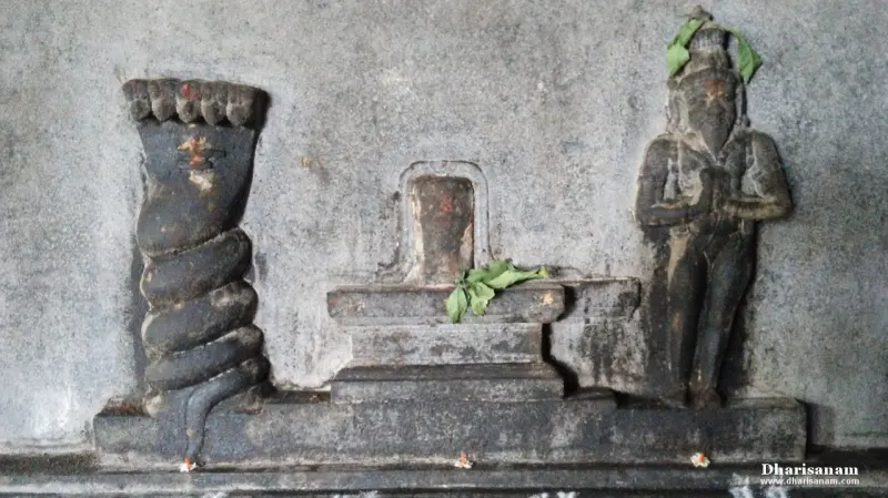 Stone relief of a lingam with a coiled snake on one side and a figure with folded hands