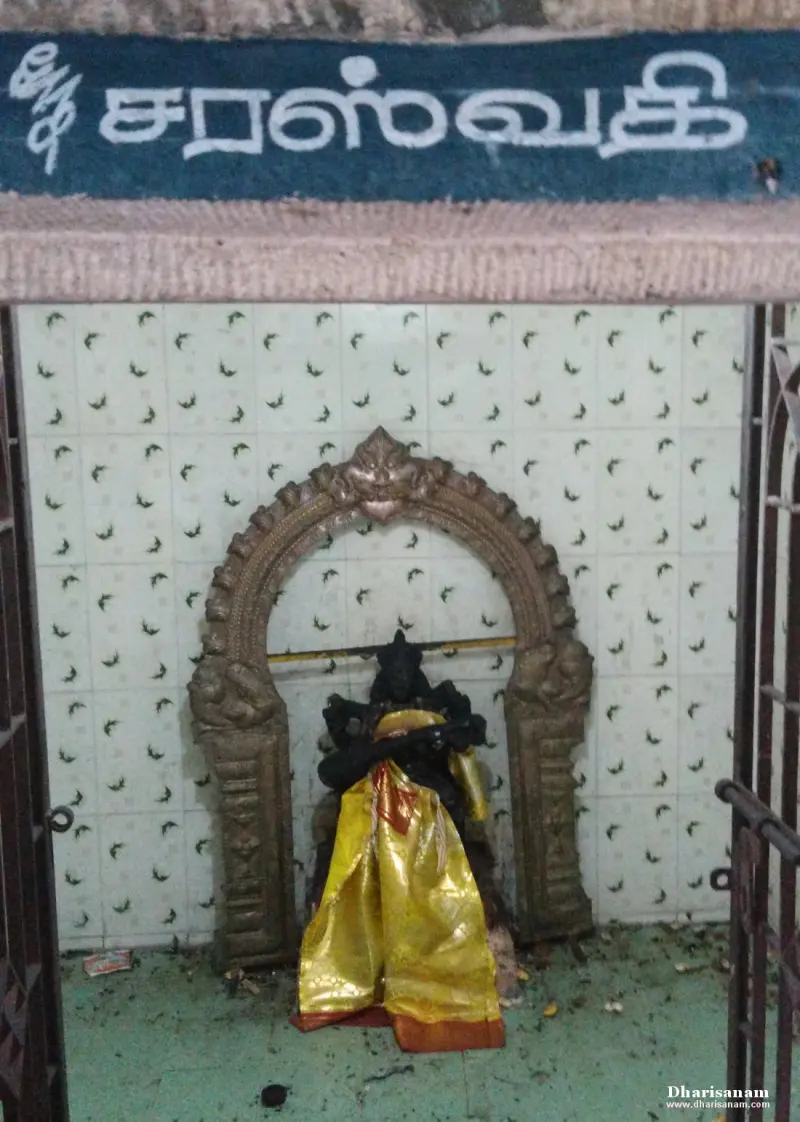 Idol draped in yellow cloth under an arch beneath a Tamil name board