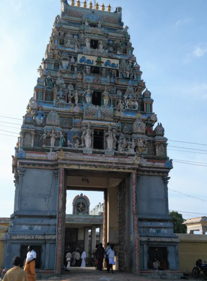 A tall painted gateway tower with many sculpted figures, and people at the open doorway below