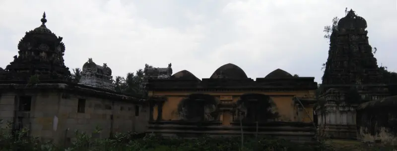 Dark shrine towers at both ends with a low yellow-walled hall and three domed roofs between them.