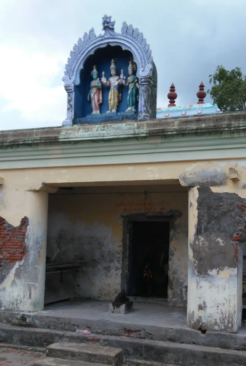 Three coloured stucco figures in a niche above a small shrine with a worn yellow porch