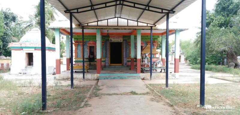 A hall with green and red pillars and an open doorway, seen through a blue-pillared tin roof