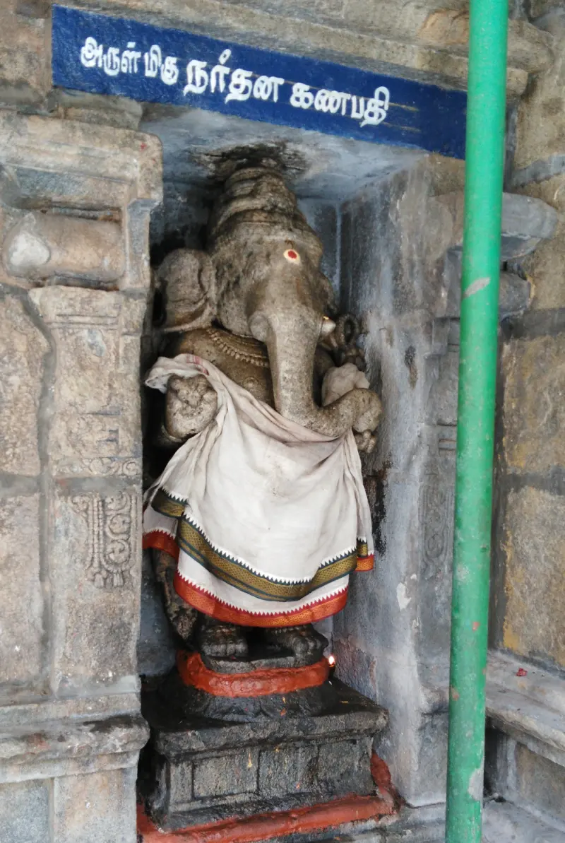 Stone Vinayakar dressed in white cloth, in a niche beneath a blue Tamil name board