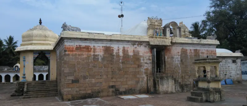 A long stone wall with a domed mandapam at the corner and a few steps leading up