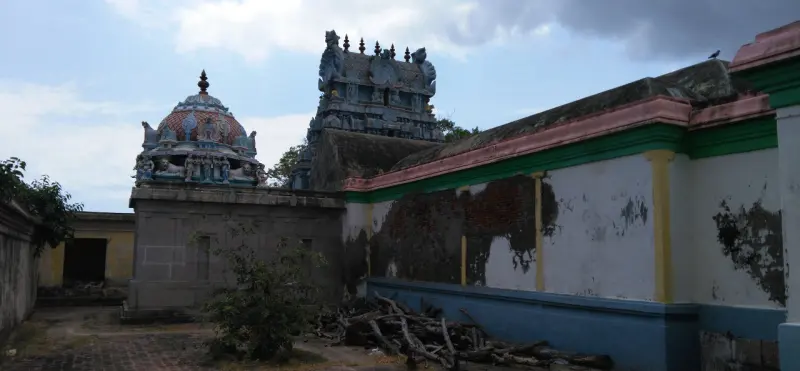 A domed shrine and a small tower rising behind a long painted corridor wall