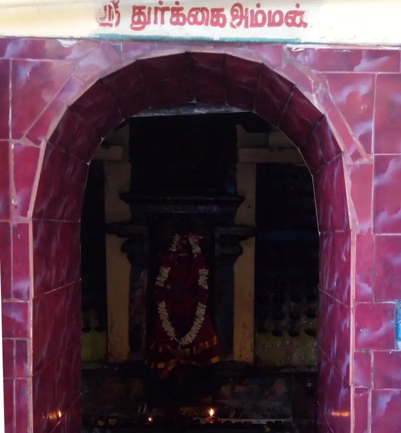Arched shrine tiled in maroon, with a garlanded image of the goddess inside and a Tamil name board