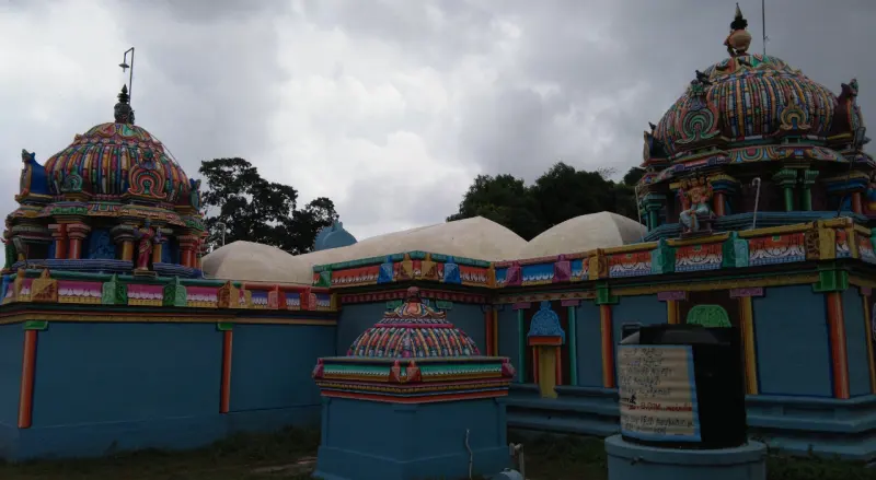 Painted shrine towers and a domed roof under a cloudy sky, with a water tank in front