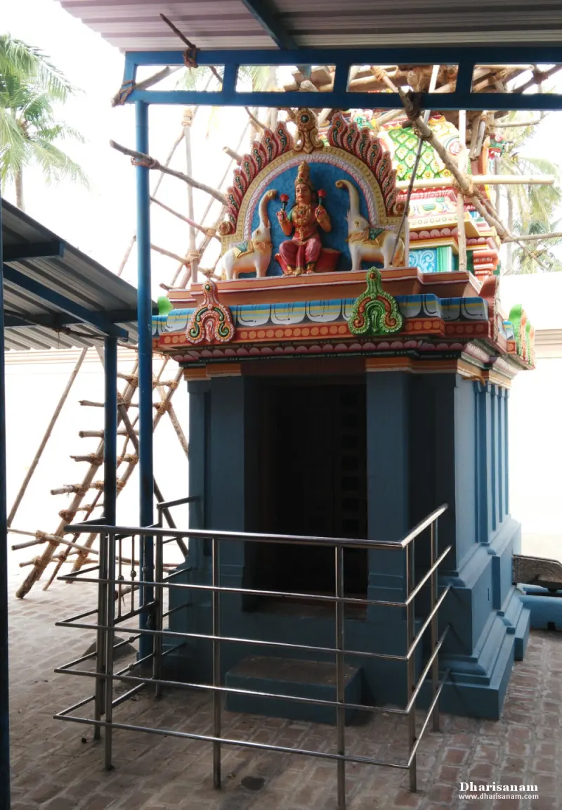 A blue shrine behind a steel railing, with a painted goddess between two elephants above
