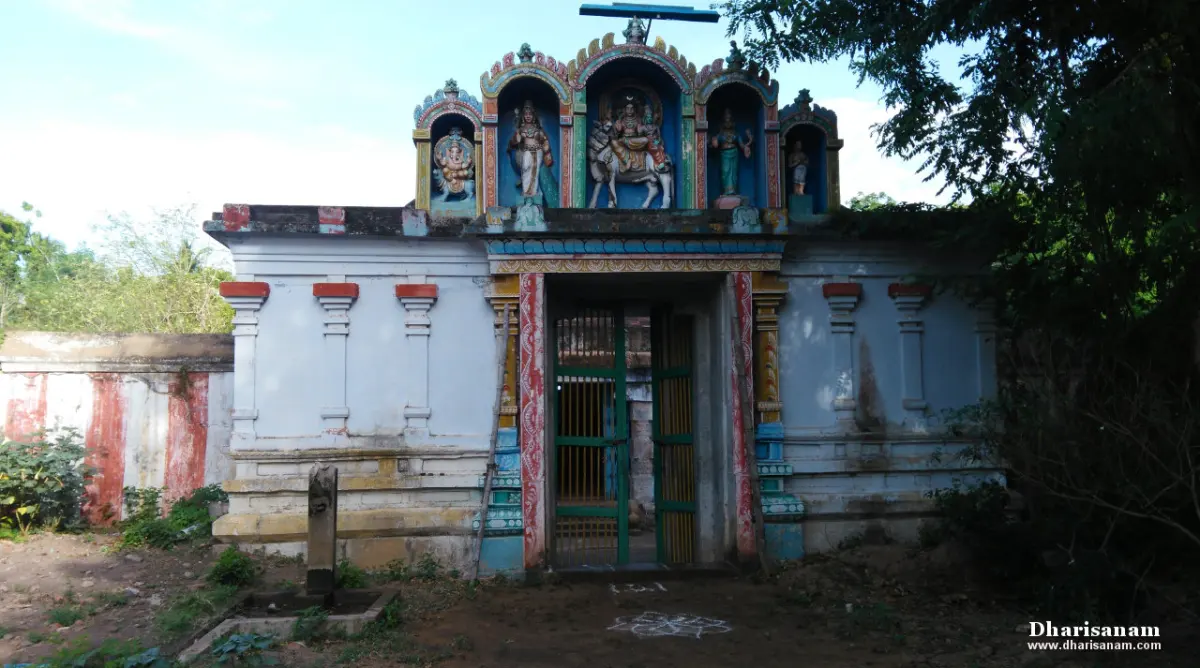 A white temple entrance with painted figures in three arched niches on top and a green gate below