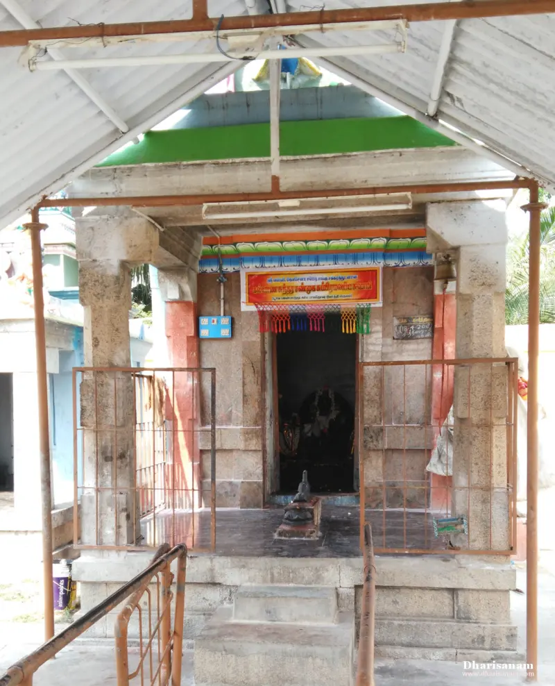 A shrine doorway with metal gates and a signboard above