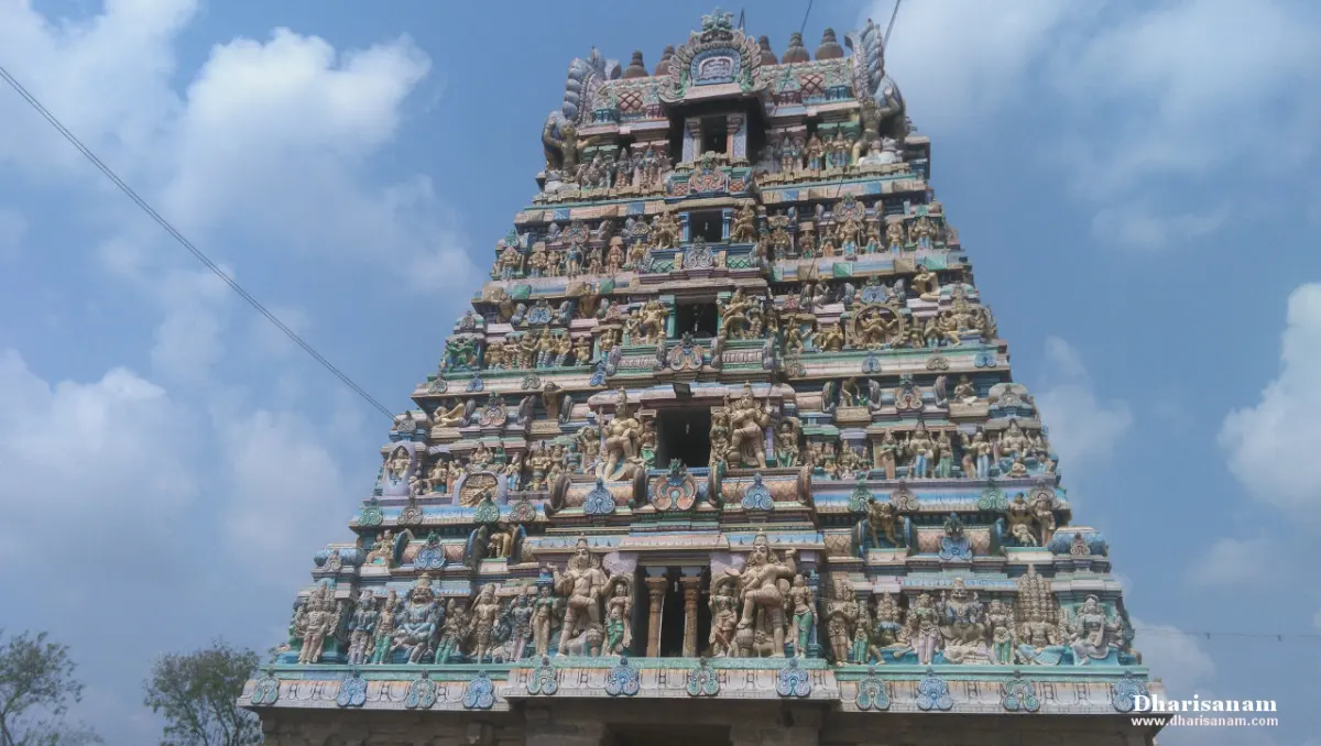Tiered gopuram covered in sculpted figures against a blue sky