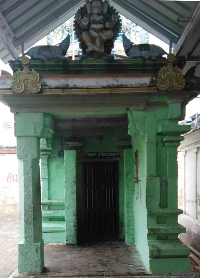 A green shrine porch with a seated Ganesha figure on top and a barred door below.