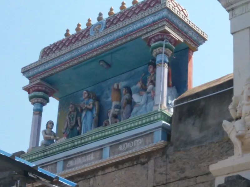 A group of coloured stucco figures standing beneath a tiled roof on a gateway