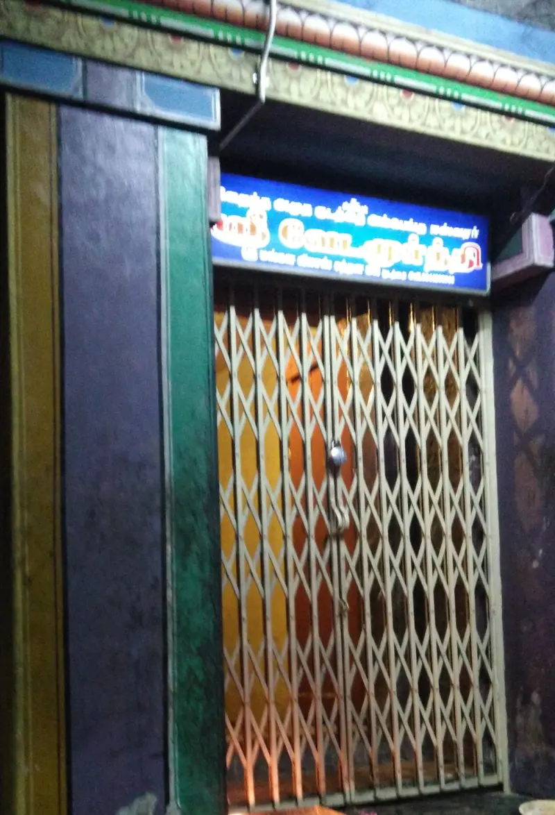 Shrine doorway shut with a steel gate under a signboard