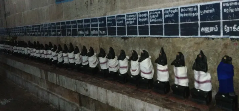 A long row of idols along the corridor wall, with name boards
