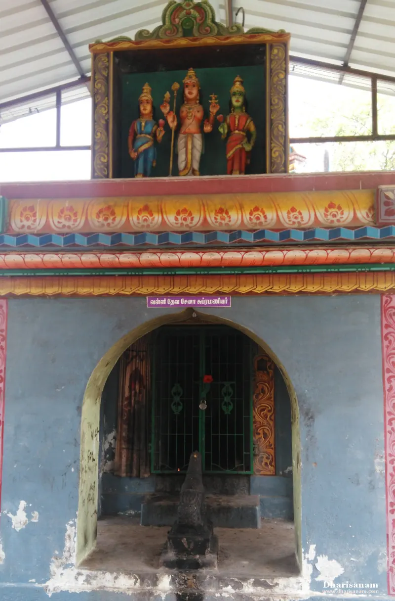 Small shrine with an arched barred doorway and a framed painting of three standing figures above it