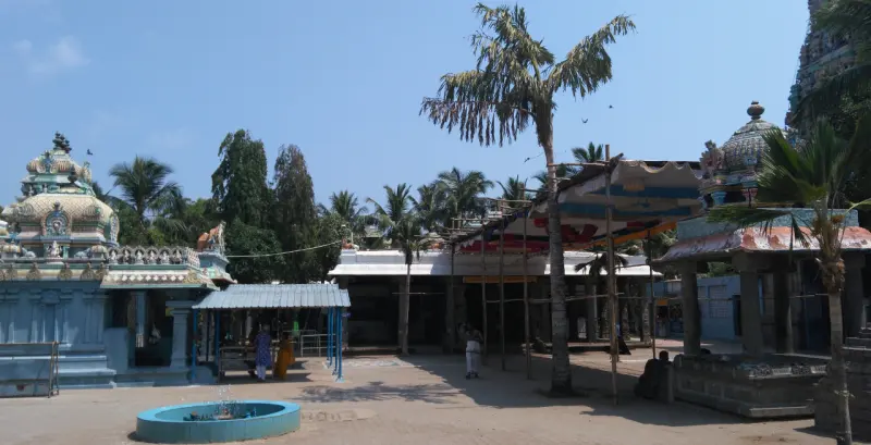 A courtyard with a blue-green fountain basin, a domed shrine at left and a corridor roof at centre.