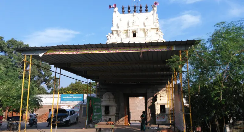 Visitors and vehicles at a covered gateway beneath a white tower