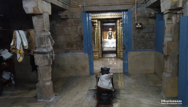 A stone-pillared hall with a small Nandhi in front, and a deity visible through the sanctum doorway ahead