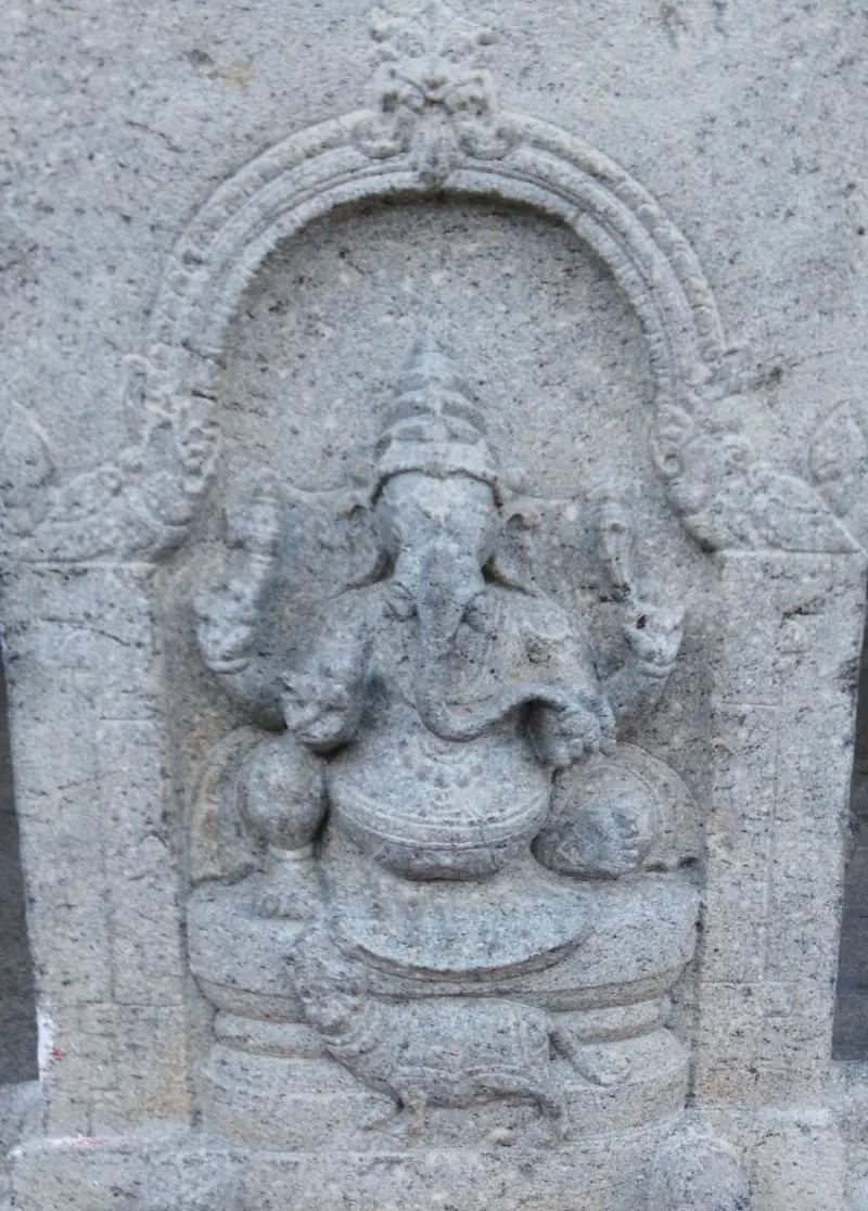 Seated elephant-headed figure under an arch, with a small mouse at its feet