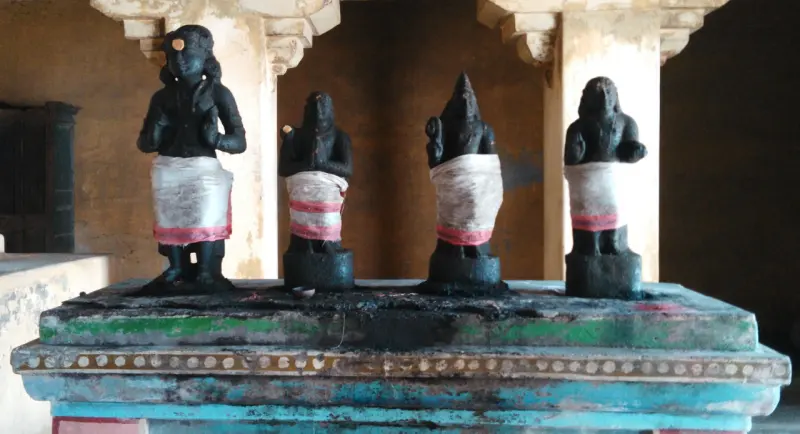 Four black standing saints with folded hands on a pedestal