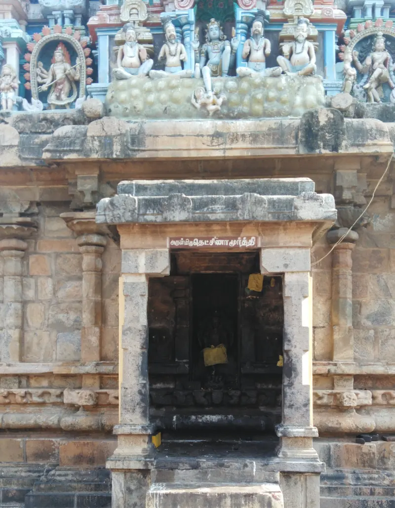 A carved stone doorway with pillars, and rows of painted figures on the tower above it