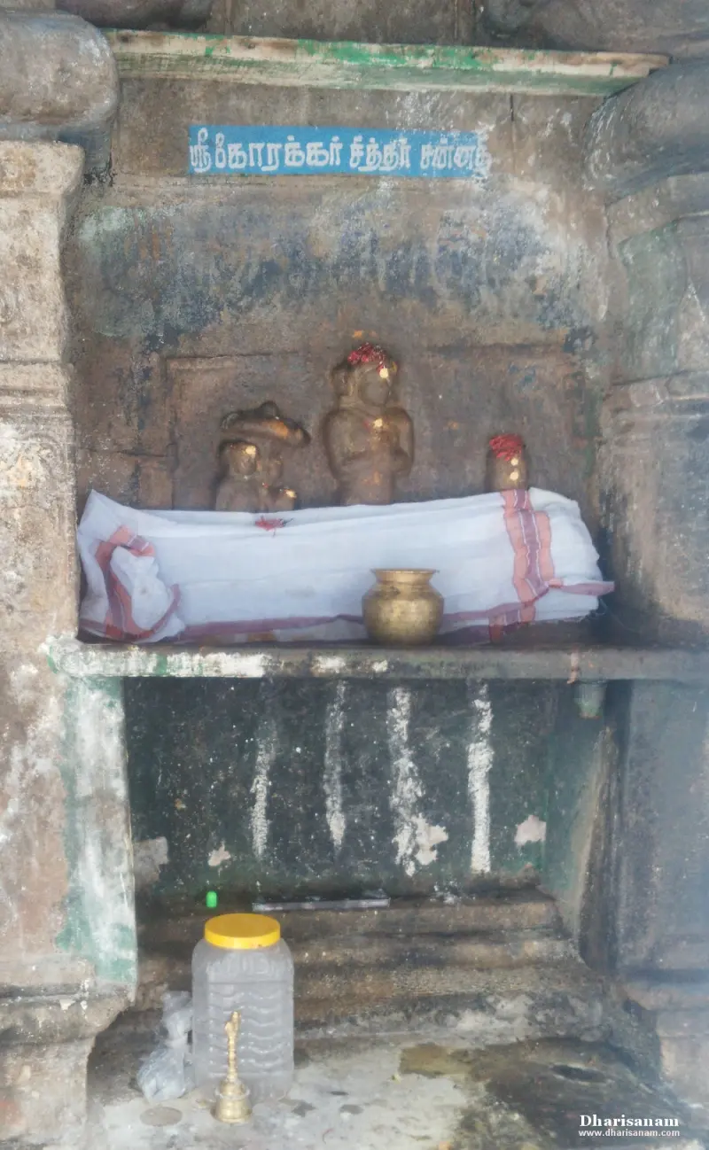 Small niche with three small idols on a white cloth, under a blue Tamil name board