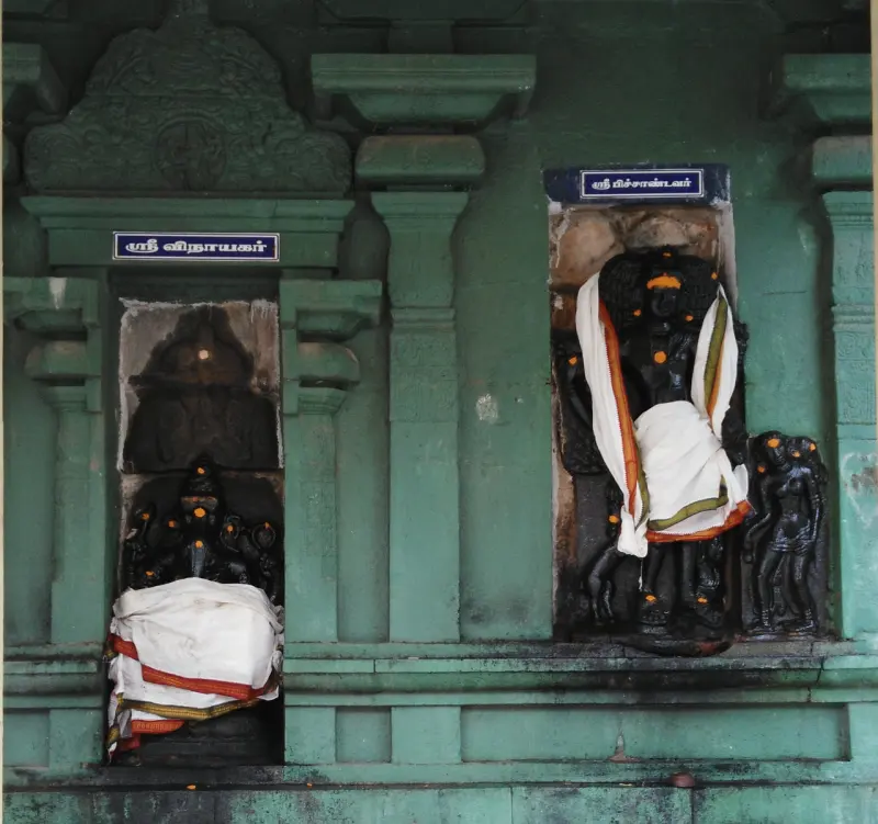 Two carved niches on a green wall, one with Vinayakar and one with Pitchandavar
