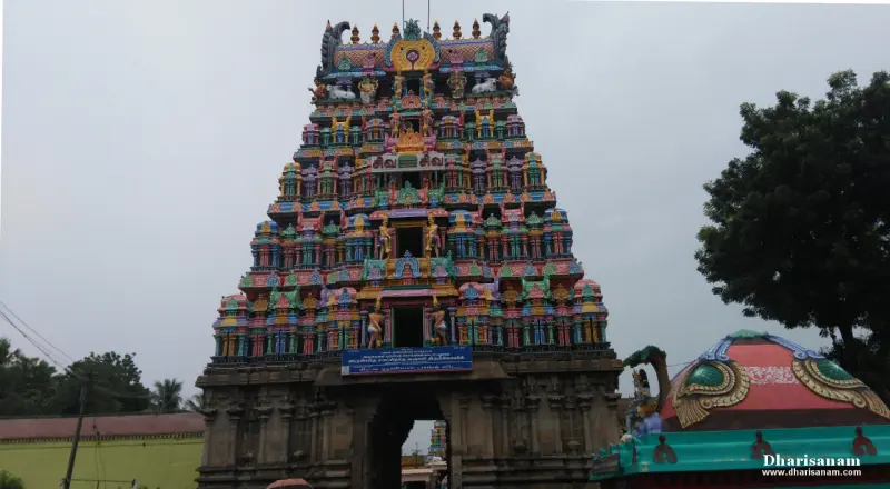Front view of the tiered, brightly painted Rajagopuram with a blue name board at its base